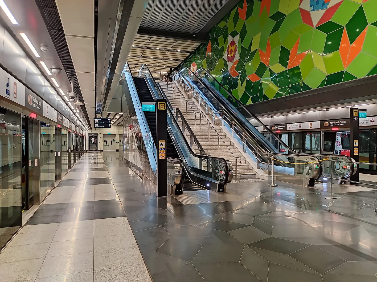 Platform level of Woodlands South MRT station (TE3) on the Thomson-East Coast Line, with escalators and a green geometric mural, the nearest station to Woodlands Drive 17 EC